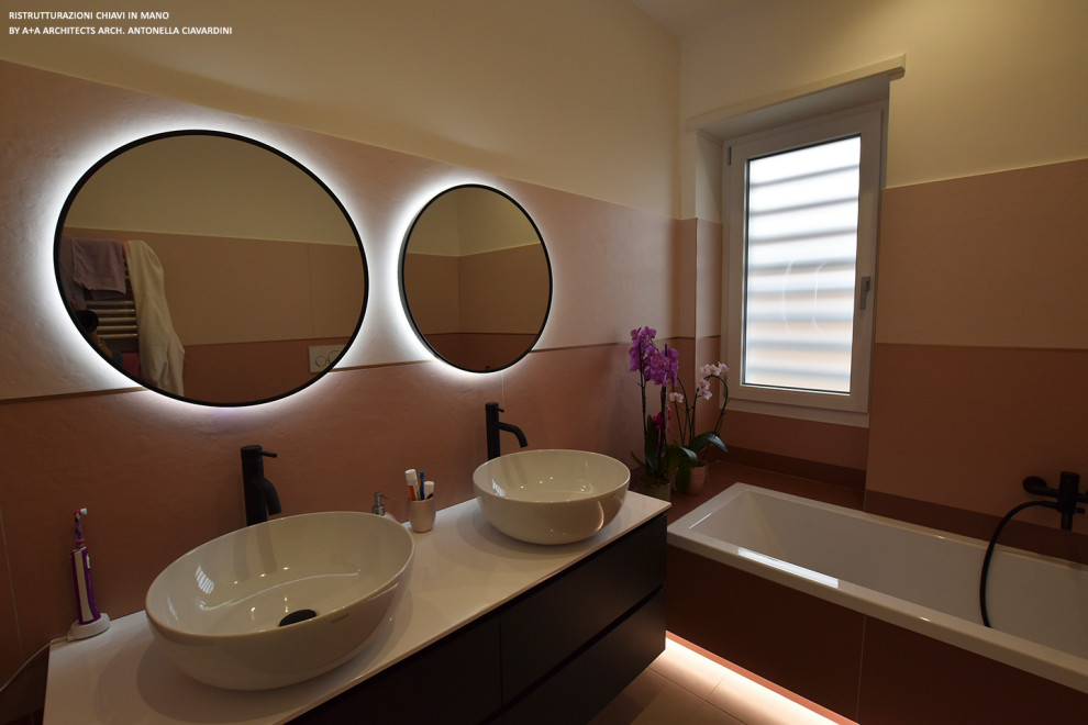 This is an example of a large contemporary family bathroom in Other with flat-panel cabinets, grey cabinets, a built-in bath, a wall mounted toilet, pink tiles, porcelain tiles, white walls, porcelain flooring, a vessel sink, grey floors, white worktops, double sinks and a floating vanity unit.
