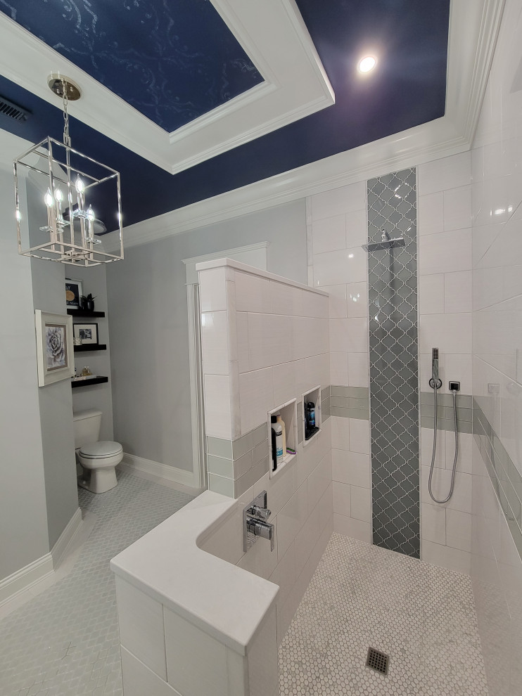 This is an example of a mid-sized transitional master bathroom in Cincinnati with shaker cabinets, white cabinets, a curbless shower, a two-piece toilet, white tile, ceramic tile, grey walls, porcelain floors, an undermount sink, quartzite benchtops, grey floor, an open shower, grey benchtops, a niche, a double vanity, a built-in vanity and recessed.