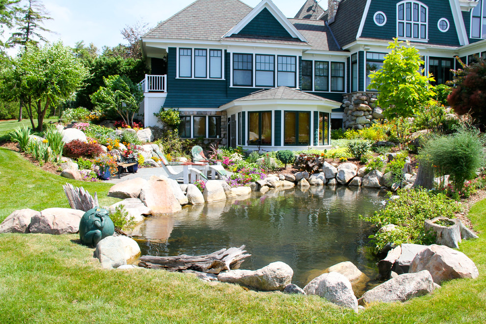 This is an example of a large tropical full sun backyard stone pond.