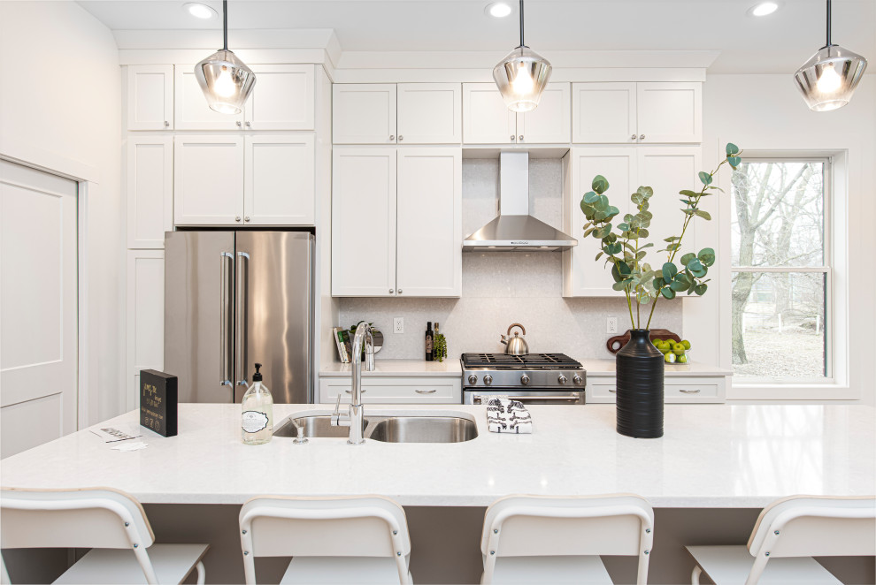 Eat-in kitchen - mid-sized transitional l-shaped eat-in kitchen idea in Indianapolis with a double-bowl sink, flat-panel cabinets, white cabinets, solid surface countertops, white backsplash, ceramic backsplash, stainless steel appliances, an island and white countertops