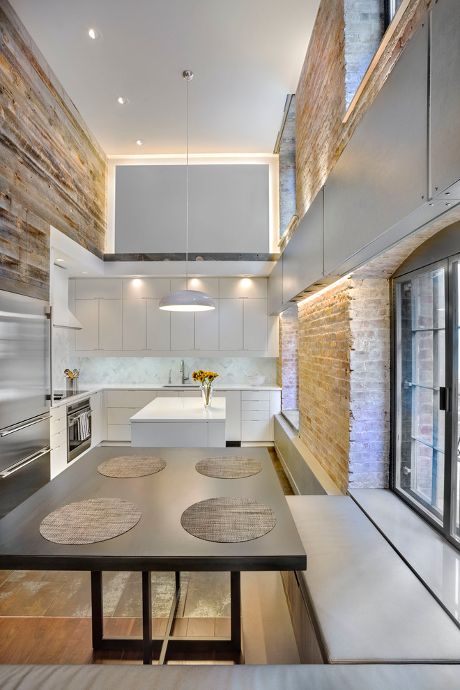 Mid-sized contemporary l-shaped eat-in kitchen in New York with flat-panel cabinets, white cabinets, white splashback, stainless steel appliances, medium hardwood floors, with island, an undermount sink, marble splashback and marble benchtops.