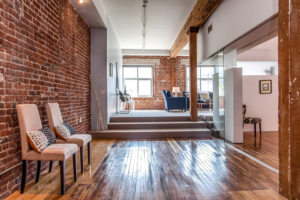 Photo of a mid-sized industrial hallway in Los Angeles with medium hardwood floors, white walls and brown floor.