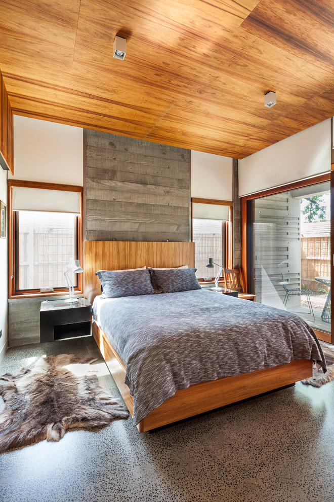 This is an example of a country master bedroom in Melbourne with white walls and concrete floors.