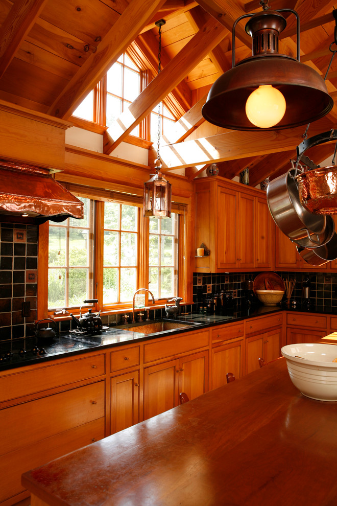 Photo of a country kitchen in Philadelphia with an undermount sink, shaker cabinets, medium wood cabinets, soapstone benchtops, black splashback, ceramic splashback and panelled appliances.