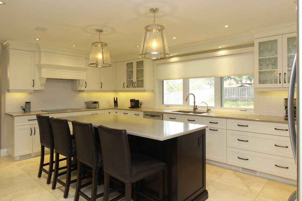 Large transitional u-shaped brown floor enclosed kitchen photo with an undermount sink, granite countertops, white backsplash, stainless steel appliances, an island and shaker cabinets