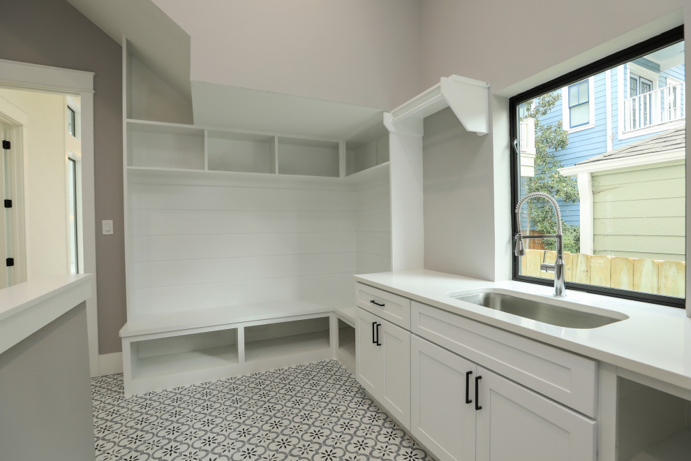 Photo of a large country u-shaped dedicated laundry room in Houston with an utility sink, shaker cabinets, white cabinets, quartzite benchtops, grey walls, porcelain floors, a side-by-side washer and dryer, multi-coloured floor and white benchtop.