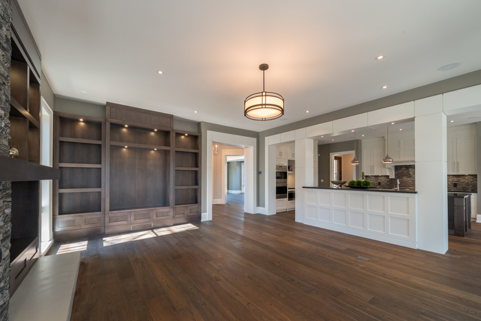 This is an example of a large open concept family room in Toronto with grey walls and medium hardwood floors.