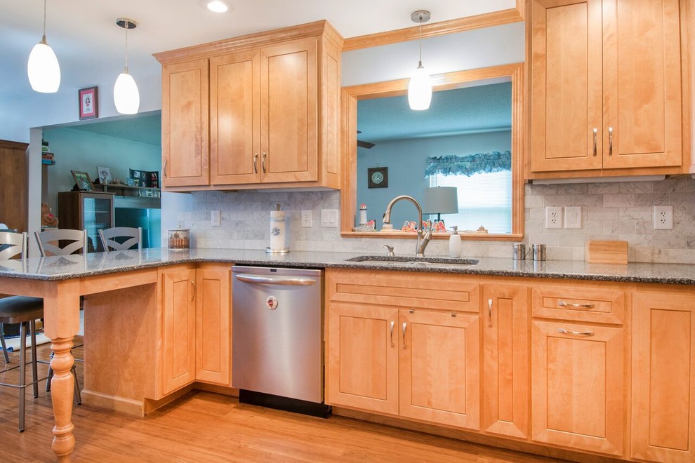 Mid-sized transitional u-shaped bamboo floor and brown floor enclosed kitchen photo in Cincinnati with a double-bowl sink, shaker cabinets, light wood cabinets, granite countertops, gray backsplash, marble backsplash, stainless steel appliances, a peninsula and gray countertops