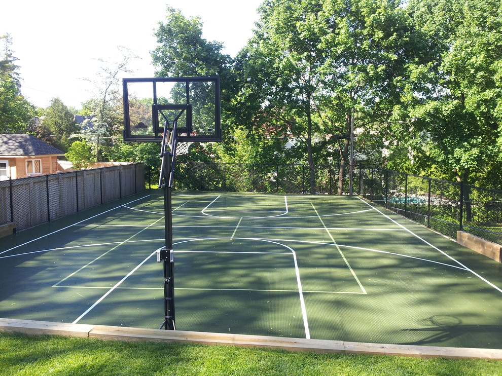 Mid-sized modern backyard partial sun outdoor sport court in Toronto with with outdoor playset and concrete pavers for summer.