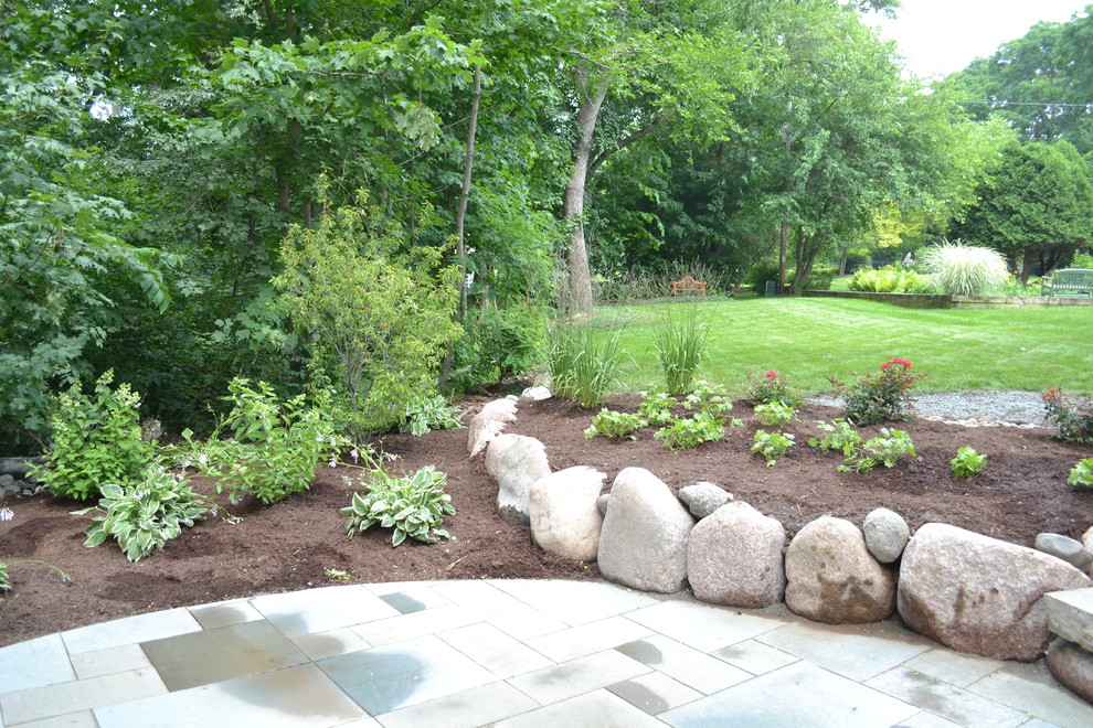Design ideas for a mid-sized rustic backyard stone landscaping in Milwaukee.