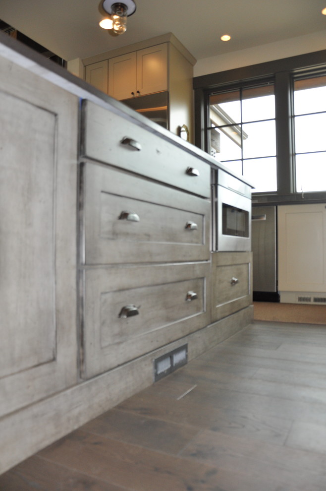 Inspiration for a large rustic l-shaped medium tone wood floor eat-in kitchen remodel in Seattle with an undermount sink, shaker cabinets, distressed cabinets, quartz countertops, gray backsplash, stone tile backsplash, stainless steel appliances and an island