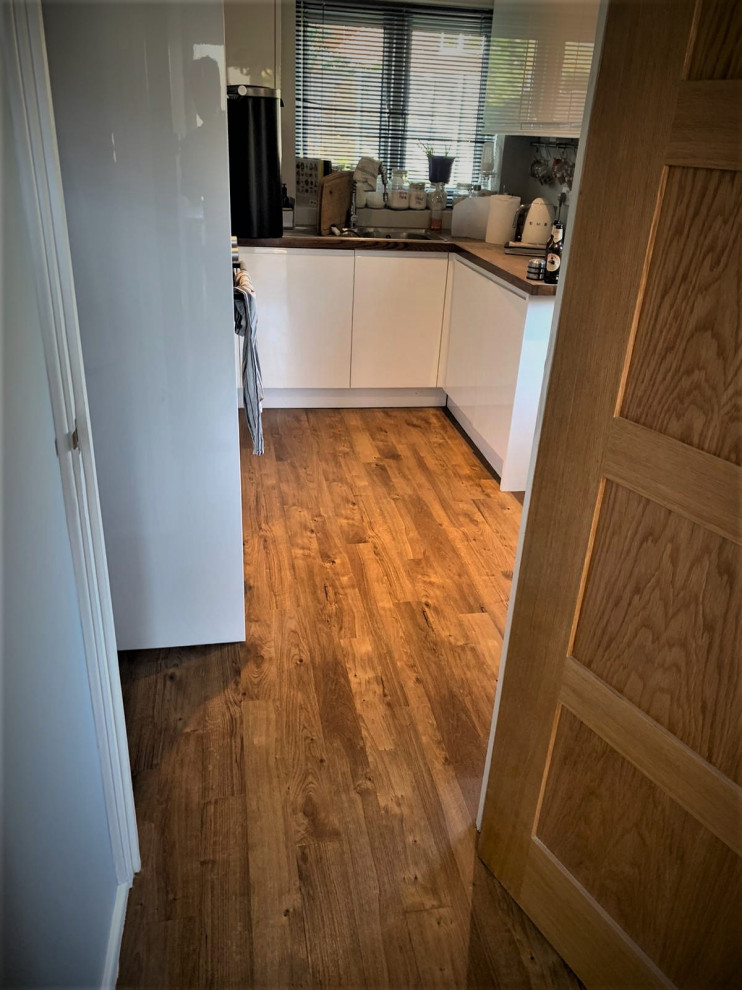 Cette image montre une petite cuisine parallèle minimaliste fermée avec un sol en vinyl et un sol marron.