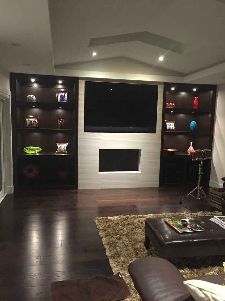 This is an example of a mid-sized contemporary enclosed home theatre in Miami with white walls, dark hardwood floors, a wall-mounted tv and brown floor.