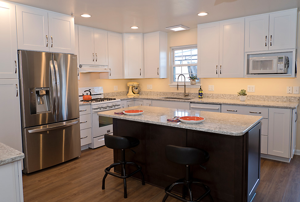 Photo of a mid-sized transitional l-shaped eat-in kitchen in Baltimore with an undermount sink, shaker cabinets, white cabinets, quartz benchtops, beige splashback, stainless steel appliances, medium hardwood floors, with island and brown floor.