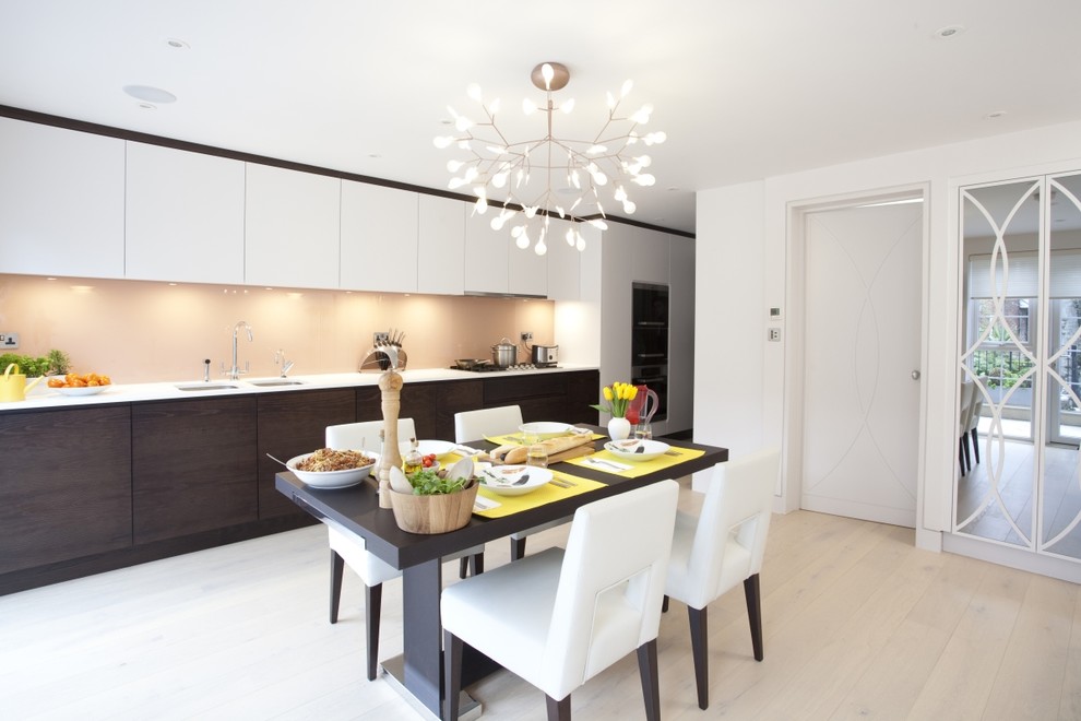 Inspiration for a large contemporary single-wall open plan kitchen in London with an undermount sink, flat-panel cabinets, dark wood cabinets, solid surface benchtops, white splashback, glass sheet splashback, stainless steel appliances, light hardwood floors and no island.