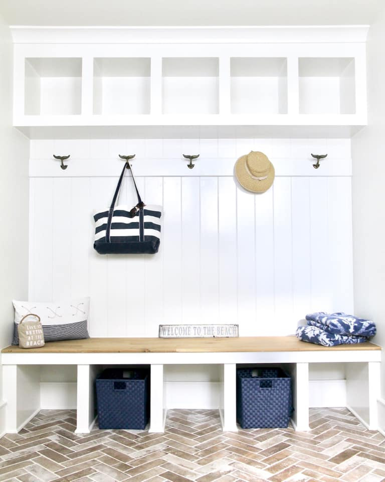 This is an example of a beach style mudroom in DC Metro with white walls, brick floors, brown floor and panelled walls.