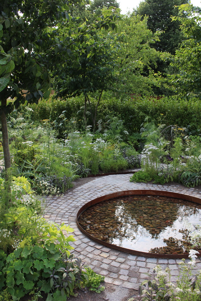 Design ideas for a small country backyard full sun xeriscape for summer in London with natural stone pavers and with pond.