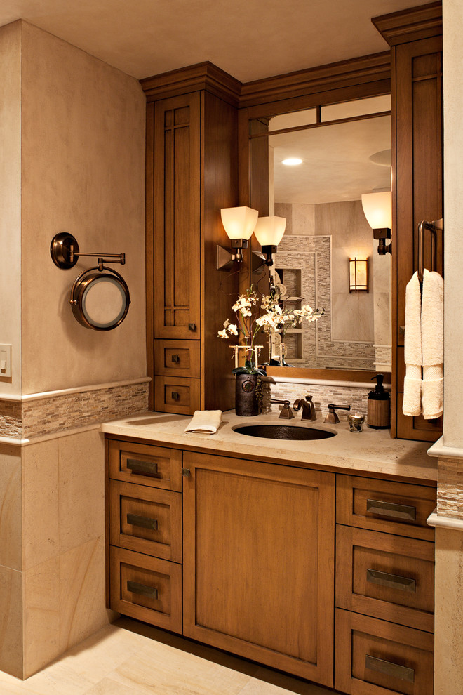 Design ideas for a mid-sized transitional master bathroom in Orange County with shaker cabinets, medium wood cabinets, a drop-in tub, a corner shower, a two-piece toilet, beige tile, stone tile, beige walls, limestone floors, an undermount sink and limestone benchtops.