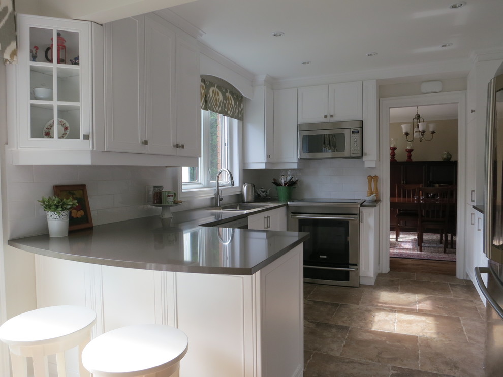 This is an example of a mid-sized traditional u-shaped eat-in kitchen in Ottawa with a double-bowl sink, shaker cabinets, white cabinets, solid surface benchtops, white splashback, subway tile splashback, stainless steel appliances, ceramic floors, a peninsula and beige floor.