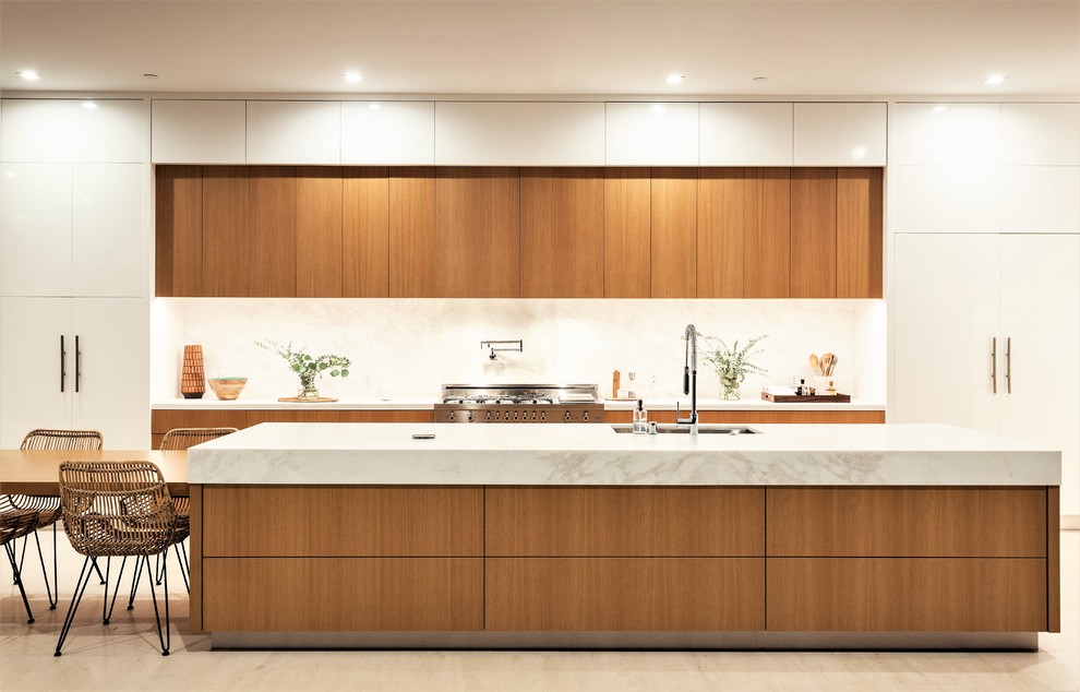 Inspiration for a large contemporary galley eat-in kitchen in Orange County with flat-panel cabinets, marble benchtops, white splashback, stone slab splashback, with island, an undermount sink, medium wood cabinets, panelled appliances, beige floor and white benchtop.