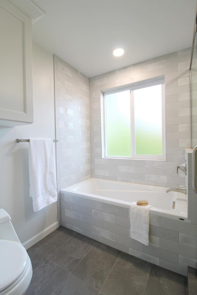 Пример оригинального дизайна: детская ванная комната среднего размера в стиле неоклассика (современная классика) с фасадами с утопленной филенкой, белыми фасадами, ванной в нише, душем в нише, унитазом-моноблоком, серой плиткой, керамической плиткой, белыми стенами, полом из керамической плитки, врезной раковиной, столешницей из искусственного кварца, серым полом, душем с распашными дверями, белой столешницей, тумбой под одну раковину и встроенной тумбой