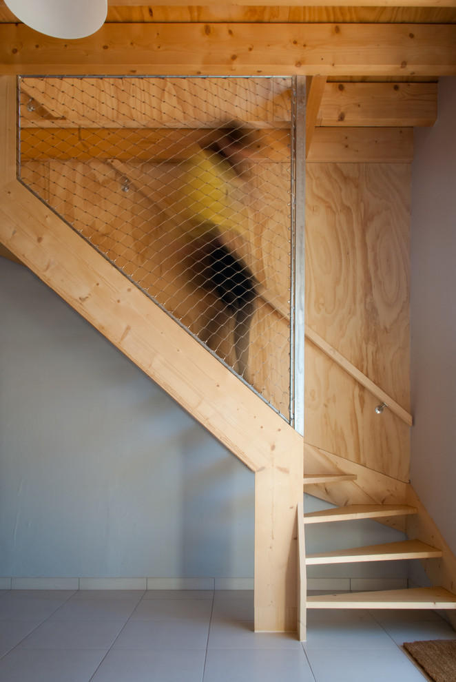 На фото: угловая лестница среднего размера в стиле лофт с деревянными ступенями без подступенок с