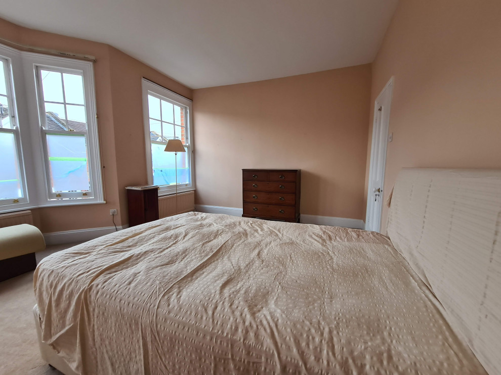 На фото: большая хозяйская спальня в классическом стиле с розовыми стенами, ковровым покрытием, бежевым полом и многоуровневым потолком