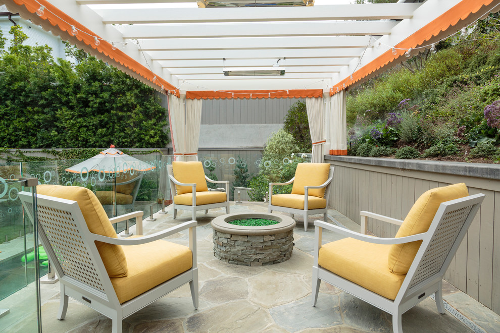 Design ideas for an expansive traditional backyard patio in Los Angeles with a fire feature, natural stone pavers and a pergola.