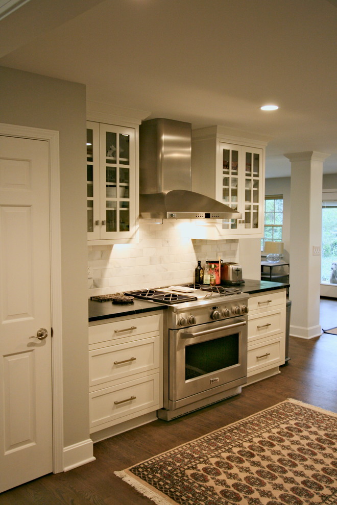 Example of a mid-sized l-shaped dark wood floor kitchen design in Cincinnati with a farmhouse sink, flat-panel cabinets, white cabinets, soapstone countertops, stainless steel appliances and a peninsula