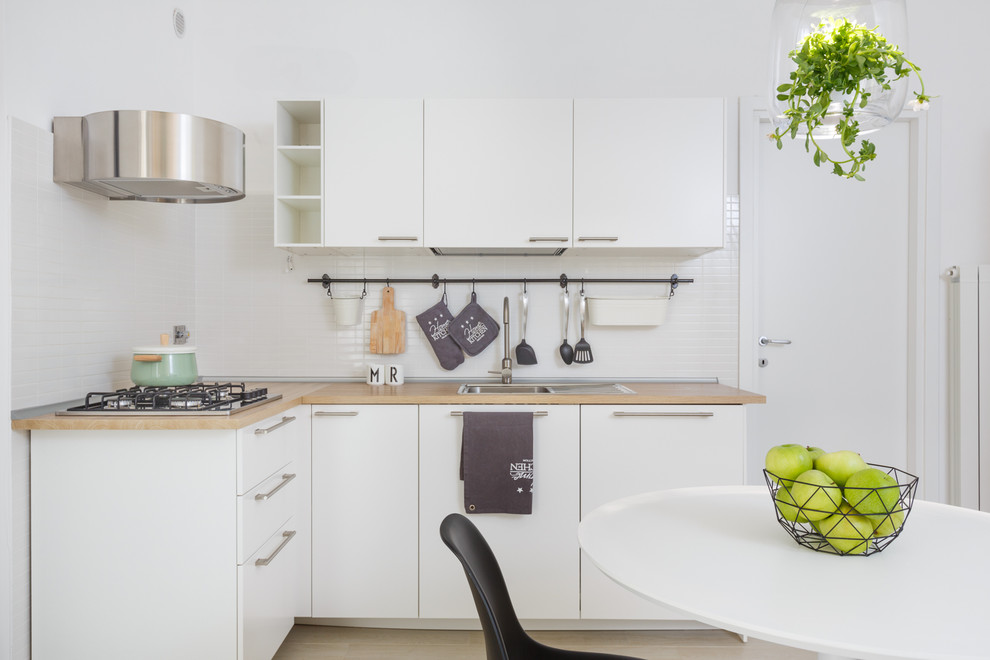 Photo of a small scandinavian l-shaped eat-in kitchen in Rome with flat-panel cabinets, white cabinets, wood benchtops, white splashback, no island, a drop-in sink and beige floor.