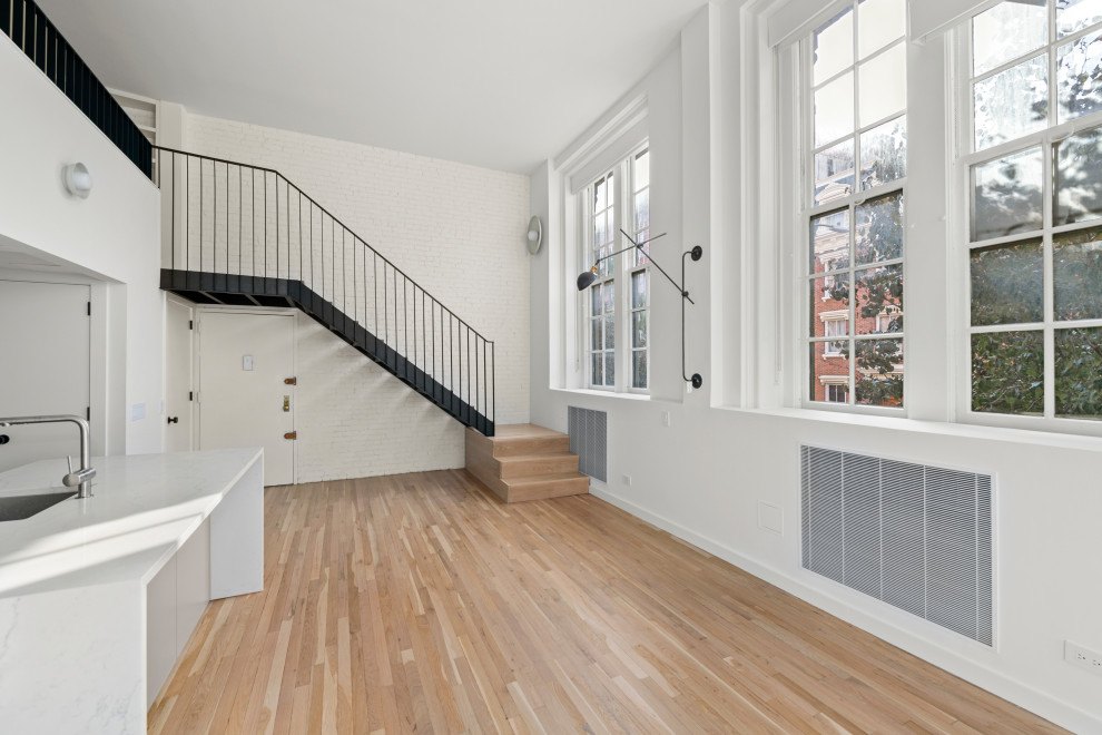 Modern inredning av ett stort loftrum, med vita väggar, ljust trägolv och beiget golv