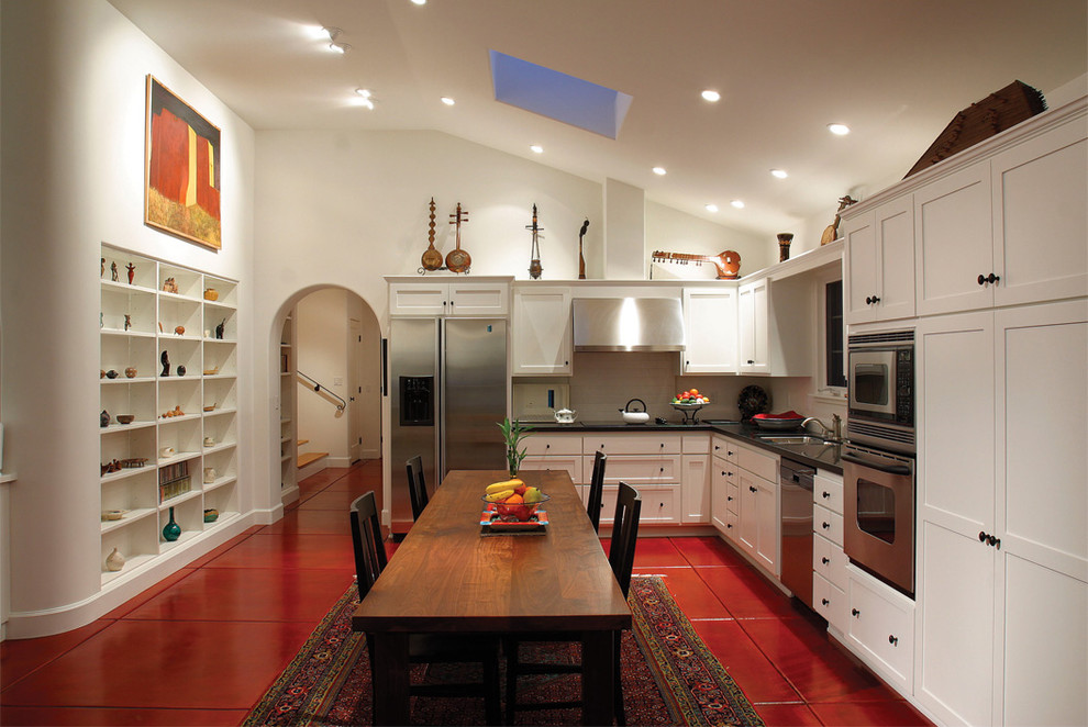 Mediterranean l-shaped kitchen in Los Angeles with shaker cabinets, white cabinets, stainless steel appliances and red floor.