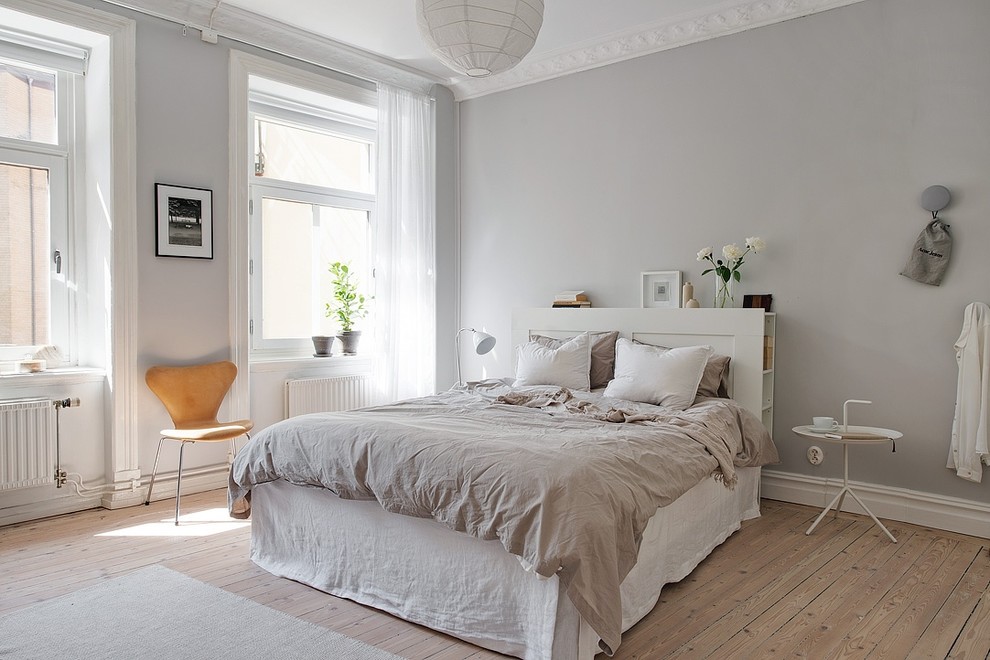 Photo of a mid-sized scandinavian master bedroom in Gothenburg with grey walls, light hardwood floors and no fireplace.