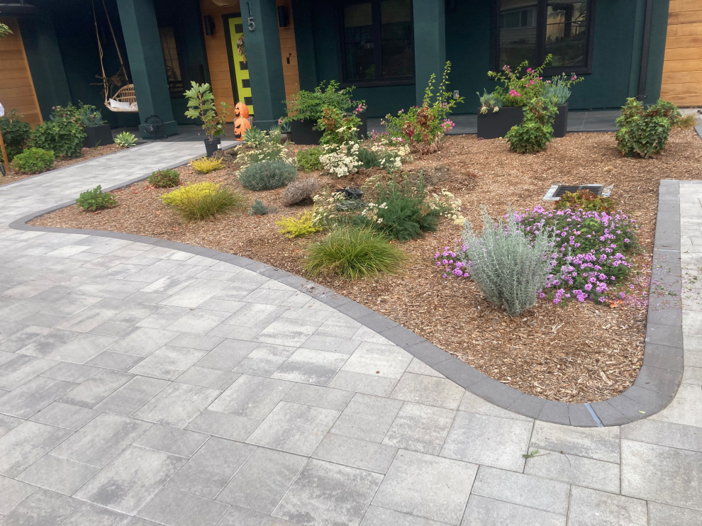 This is an example of a large midcentury front yard driveway in San Francisco with with flowerbed and brick pavers.