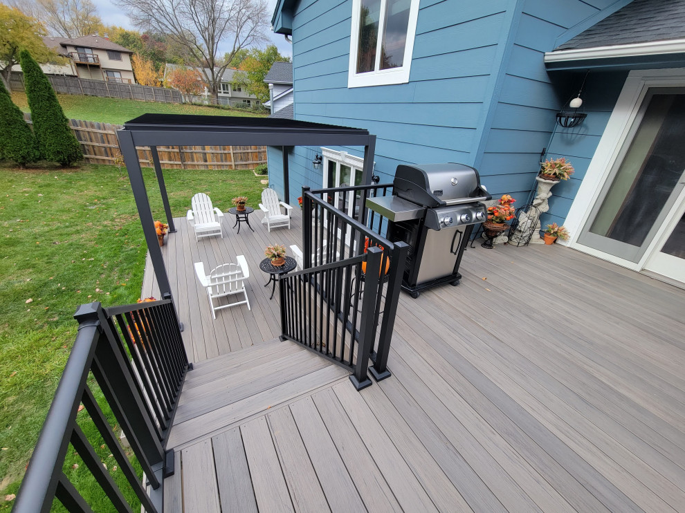 Example of a large backyard ground level metal railing deck design with a pergola