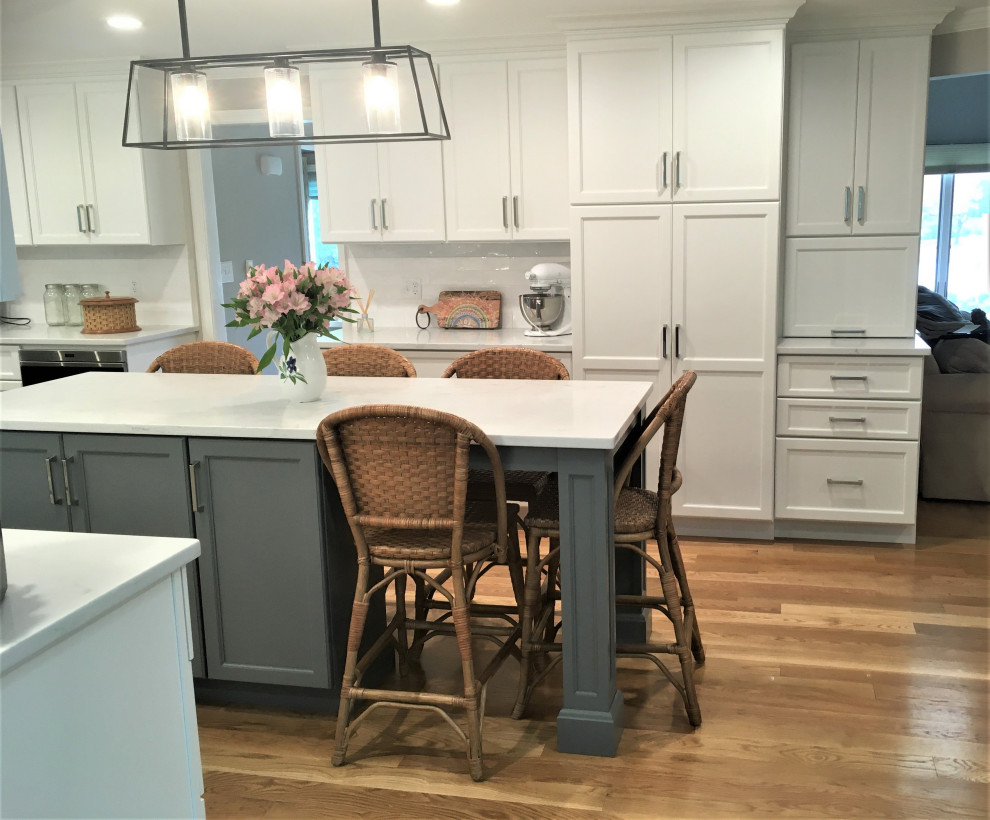Large transitional galley light wood floor and brown floor eat-in kitchen photo in Boston with an undermount sink, shaker cabinets, white cabinets, quartz countertops, white backsplash, subway tile backsplash, stainless steel appliances, two islands and white countertops