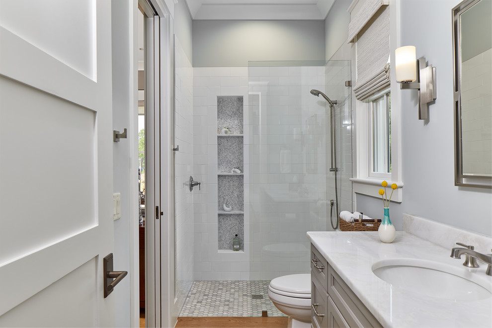 Mid-sized beach style master bathroom in Charleston with white cabinets, an open shower, a wall-mount toilet, gray tile, ceramic tile, grey walls, medium hardwood floors, a drop-in sink, brown floor, an open shower and white benchtops.