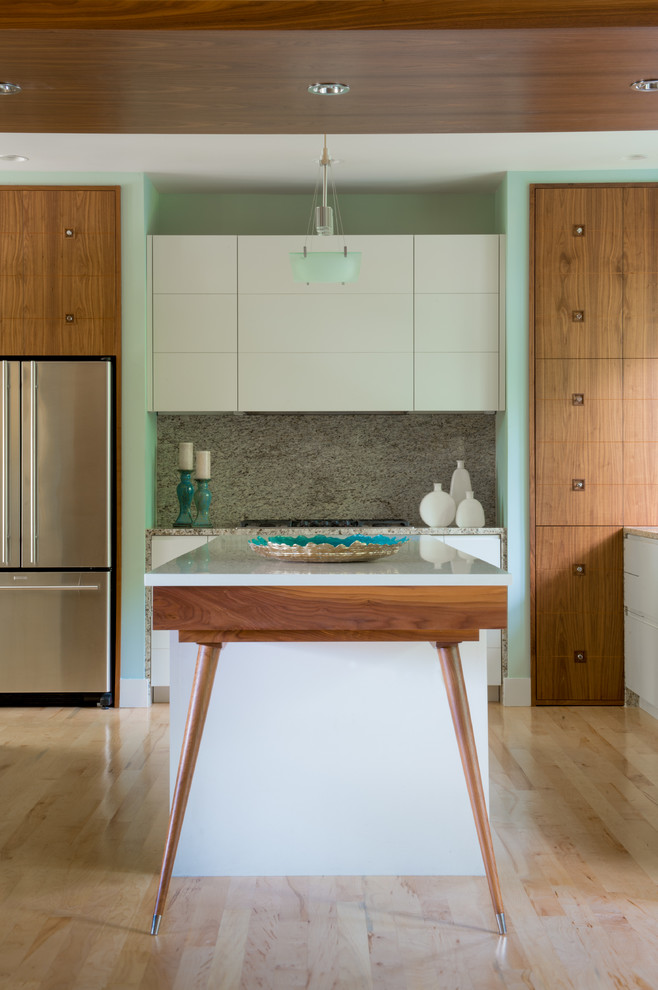 Photo of a mid-sized midcentury single-wall eat-in kitchen in Atlanta with flat-panel cabinets, medium wood cabinets, solid surface benchtops, beige splashback, stone slab splashback, stainless steel appliances, light hardwood floors and with island.