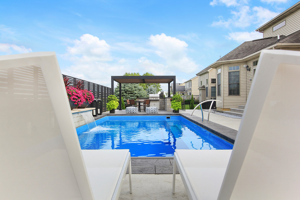 Example of a large transitional backyard stamped concrete and rectangular lap pool fountain design in Chicago