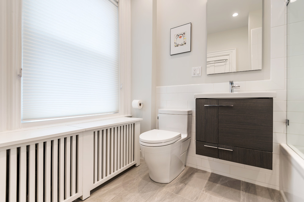 Photo of a mid-sized contemporary bathroom in Boston with flat-panel cabinets, dark wood cabinets, an alcove tub, a shower/bathtub combo, a one-piece toilet, white tile, subway tile, white walls, porcelain floors, an integrated sink, solid surface benchtops and an open shower.