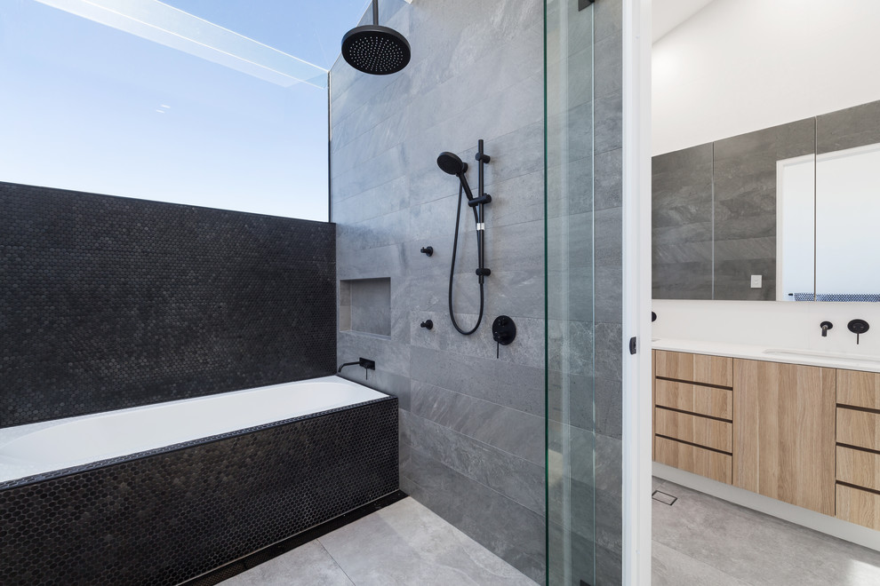 Inspiration for a mid-sized contemporary master bathroom in Sydney with medium wood cabinets, a drop-in tub, gray tile, black tile, porcelain tile, white walls, porcelain floors, laminate benchtops, grey floor, an open shower, flat-panel cabinets, a shower/bathtub combo, an undermount sink and white benchtops.