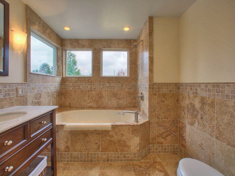 Inspiration for a mid-sized traditional master bathroom in Seattle with furniture-like cabinets, brown cabinets, a drop-in tub, a shower/bathtub combo, a one-piece toilet, brown tile, stone tile, beige walls, an undermount sink, marble benchtops, brown floor and an open shower.
