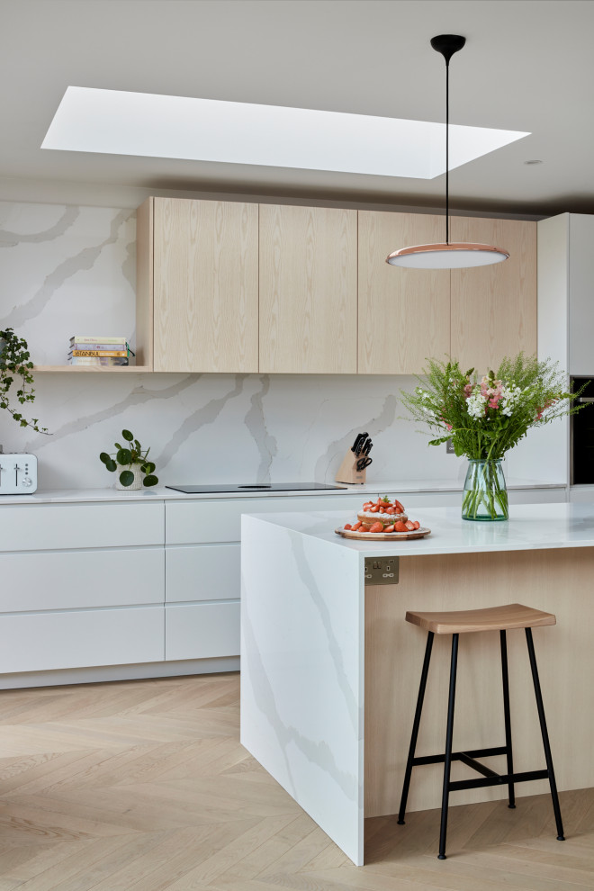 This is an example of a large scandinavian l-shaped kitchen in London with flat-panel cabinets, white cabinets, quartzite benchtops, white splashback, with island and white benchtop.