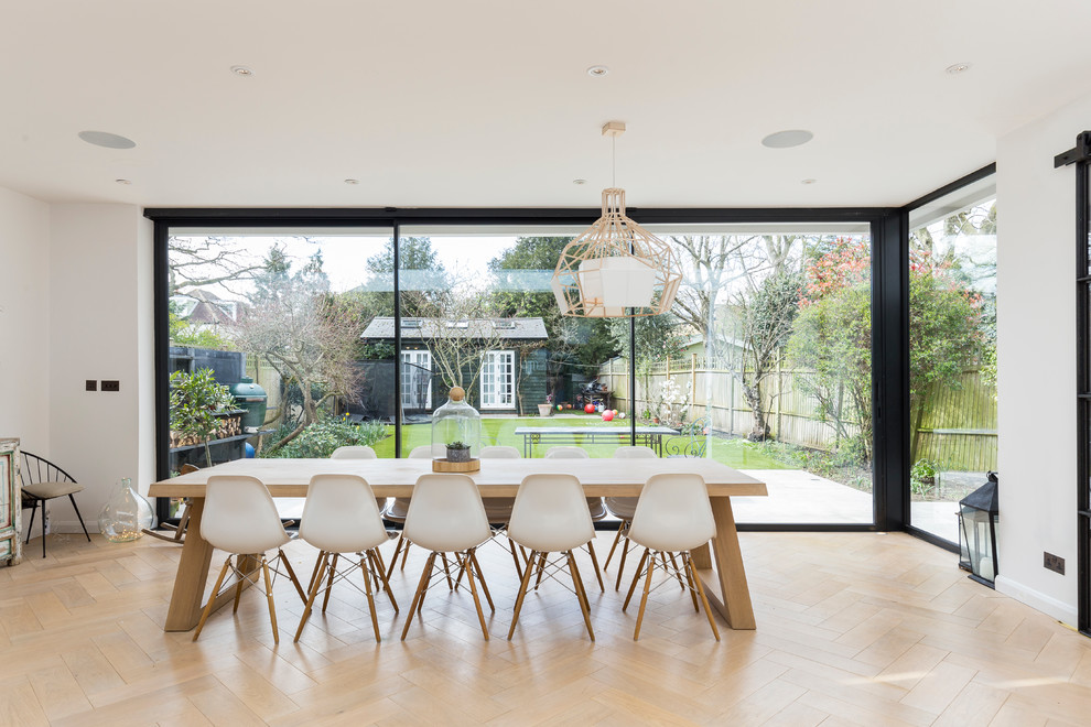 Photo of a contemporary dining room in London with white walls and light hardwood floors.