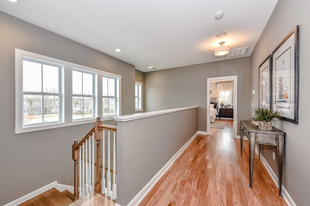 This is an example of a small transitional hallway in Charlotte with grey walls and light hardwood floors.