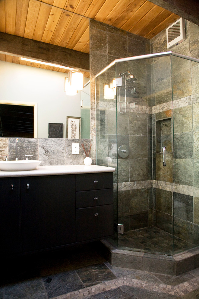 This is an example of a contemporary master bathroom in Seattle with a corner shower, a vessel sink, flat-panel cabinets, dark wood cabinets, gray tile, multi-coloured tile, stone tile, grey walls, pebble tile floors and limestone benchtops.