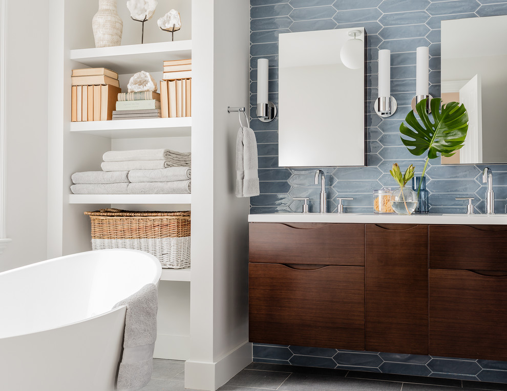 This is an example of a contemporary master bathroom in Boston with flat-panel cabinets, dark wood cabinets, a freestanding tub, an alcove shower, blue tile, grey floor, white walls and an undermount sink.