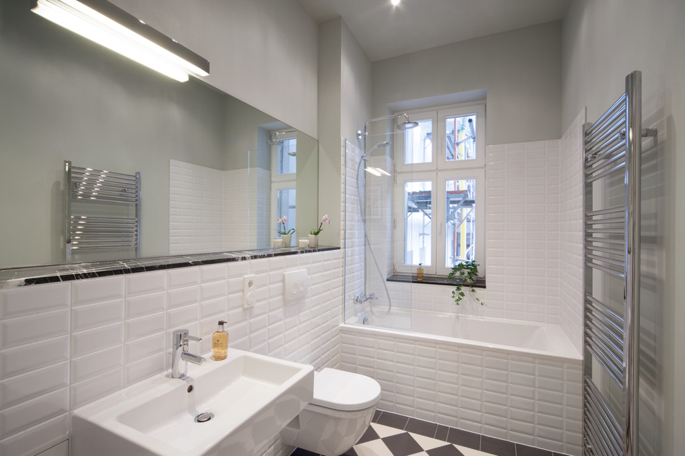 Small bathroom in Berlin with a drop-in tub, a wall-mount toilet, subway tile, white walls, cement tiles, a wall-mount sink and multi-coloured floor.