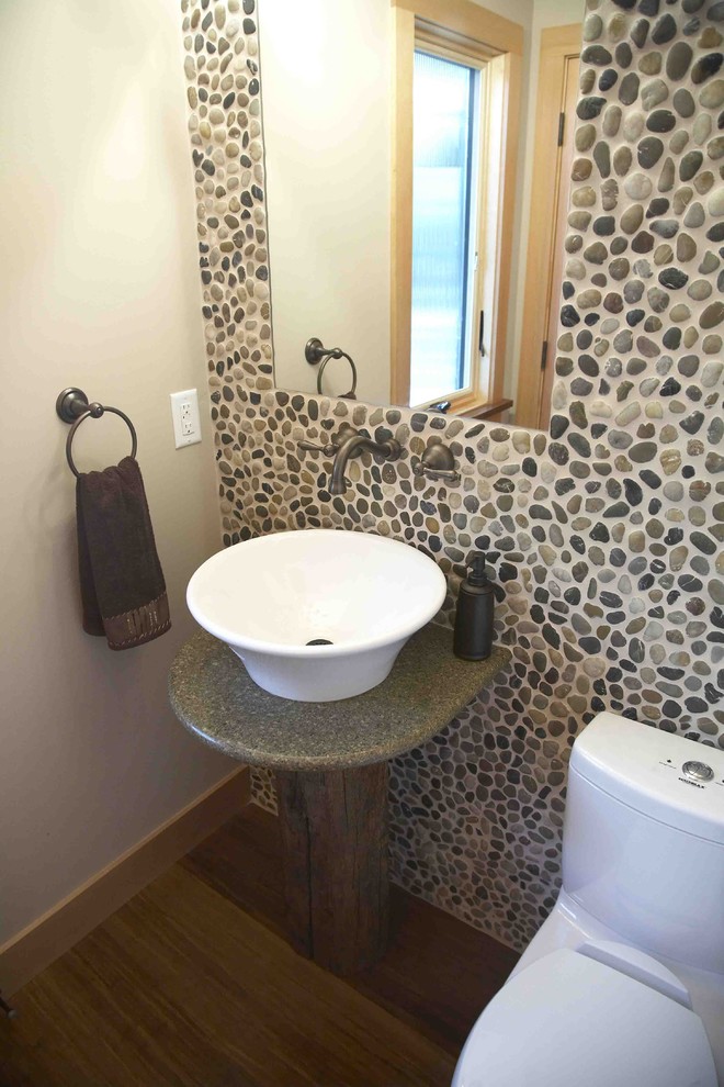 This is an example of a small country powder room in San Francisco with a vessel sink, pebble tile, granite benchtops, a two-piece toilet, beige walls, gray tile, bamboo floors, brown floor and green benchtops.