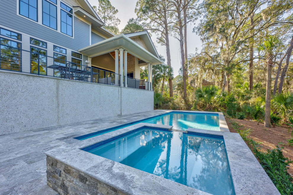 Immagine di una piscina monocorsia stile marino rettangolare di medie dimensioni e dietro casa con una vasca idromassaggio e pavimentazioni in pietra naturale